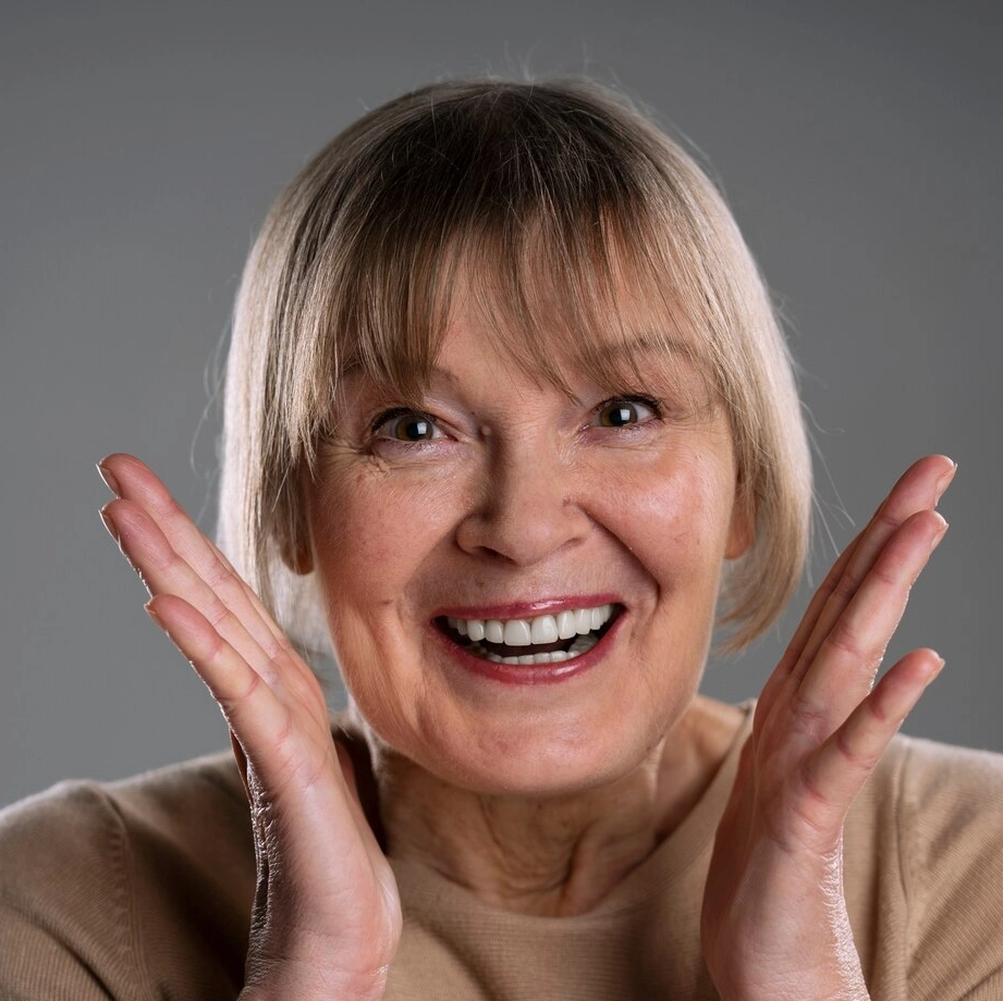 Smiling elderly woman with dentures, showing satisfaction with dental care at Six Point Dental.