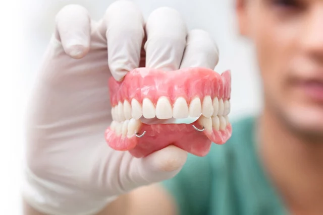 Dental professional holding custom dentures, illustrating high-quality denture services at Six Point Dental.