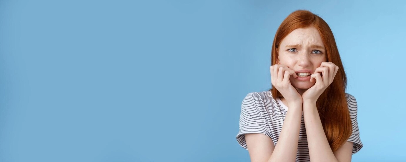 Girl holding her mouth experiencing tooth pain on blue background